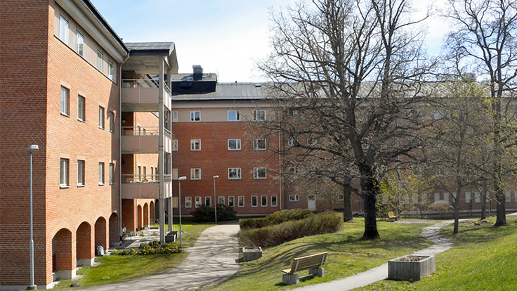 Stort rött tegelhus vid grön park